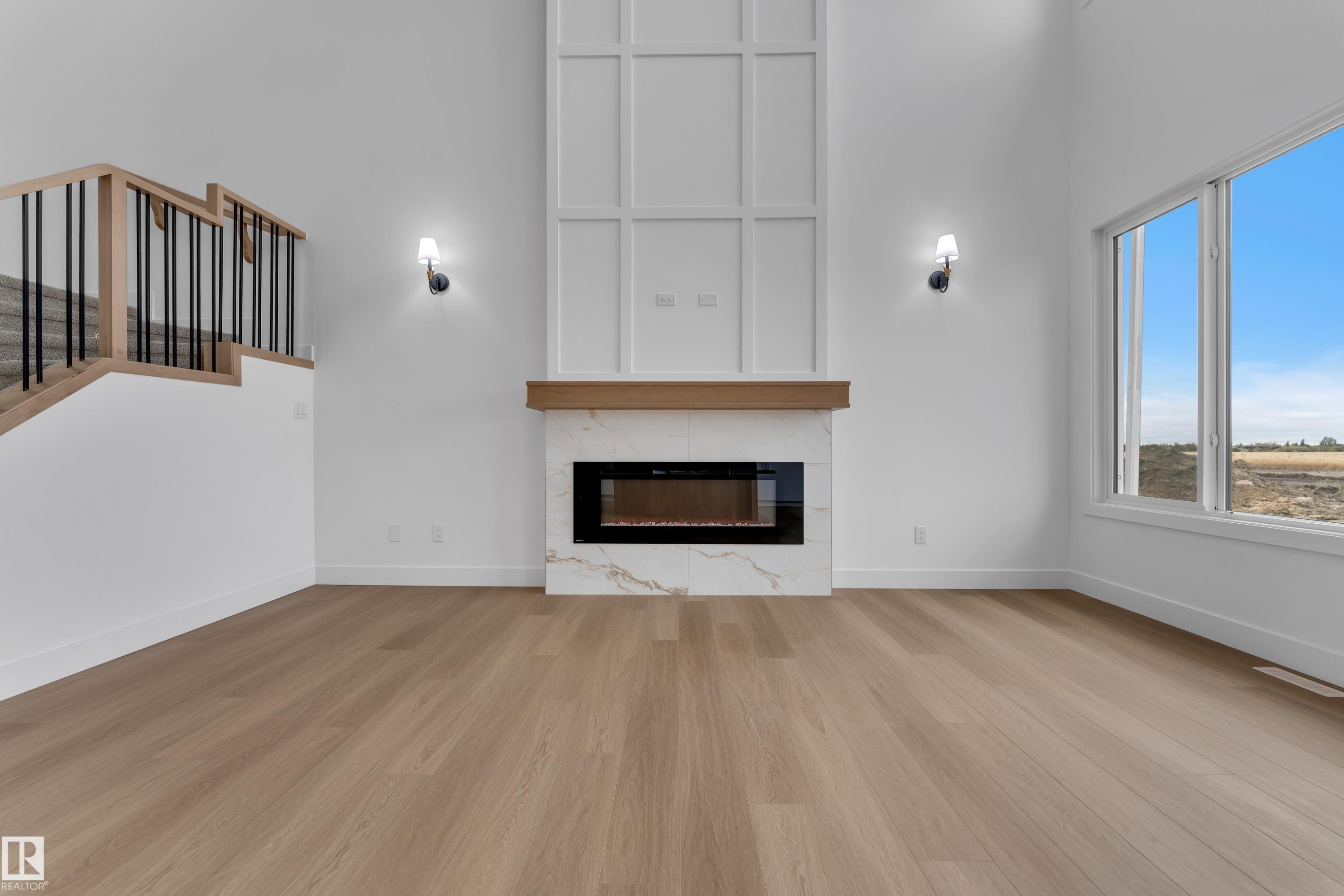 Wood-finish flooring throughout, featuring a modern fireplace with a white marble-look surround and wood mantel - 794 Bank Drive, Leduc, AB