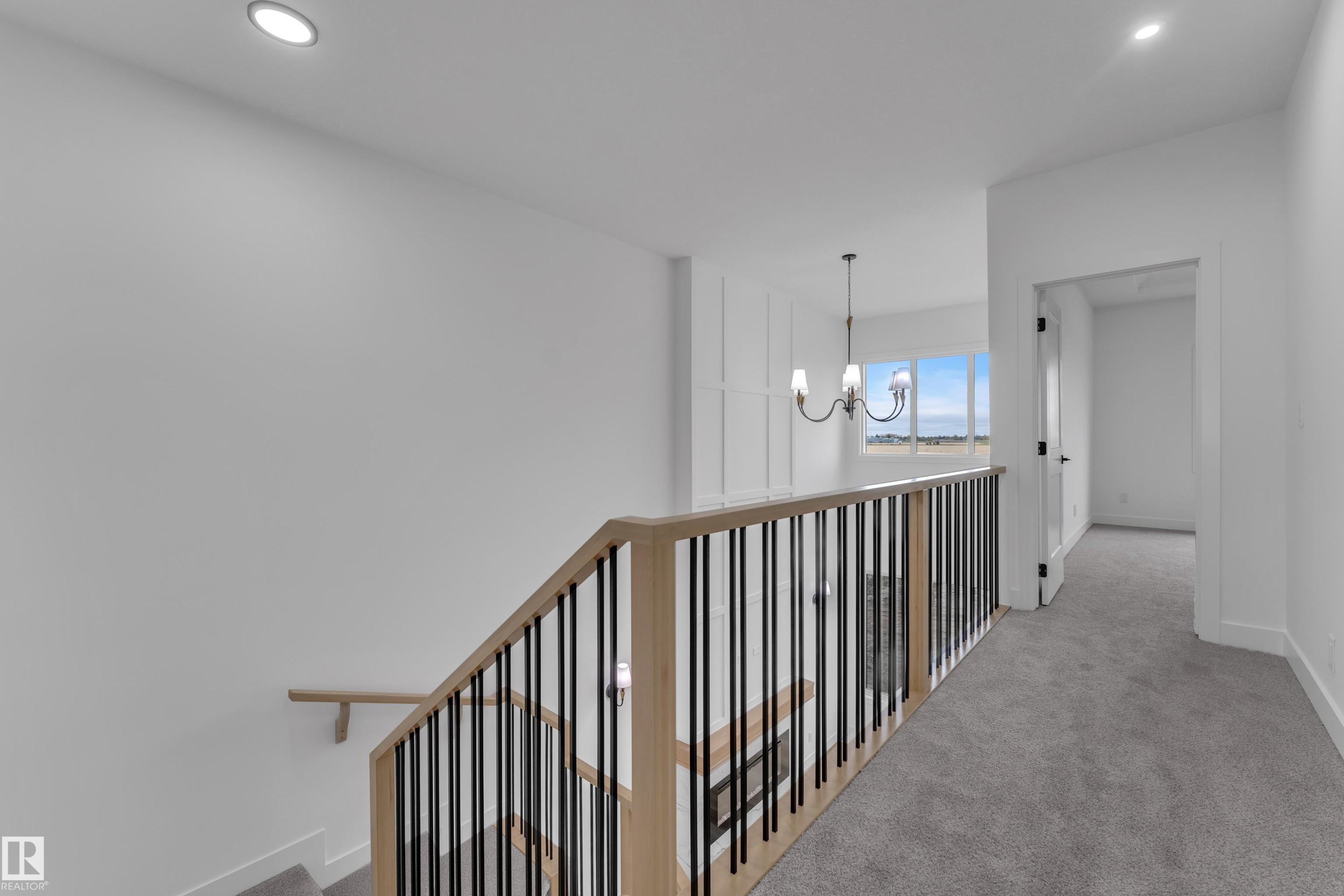 Upper level hallway featuring recessed lighting, a chandelier, wood and metal banister, and carpeted flooring - 794 Bank Drive, Leduc, AB