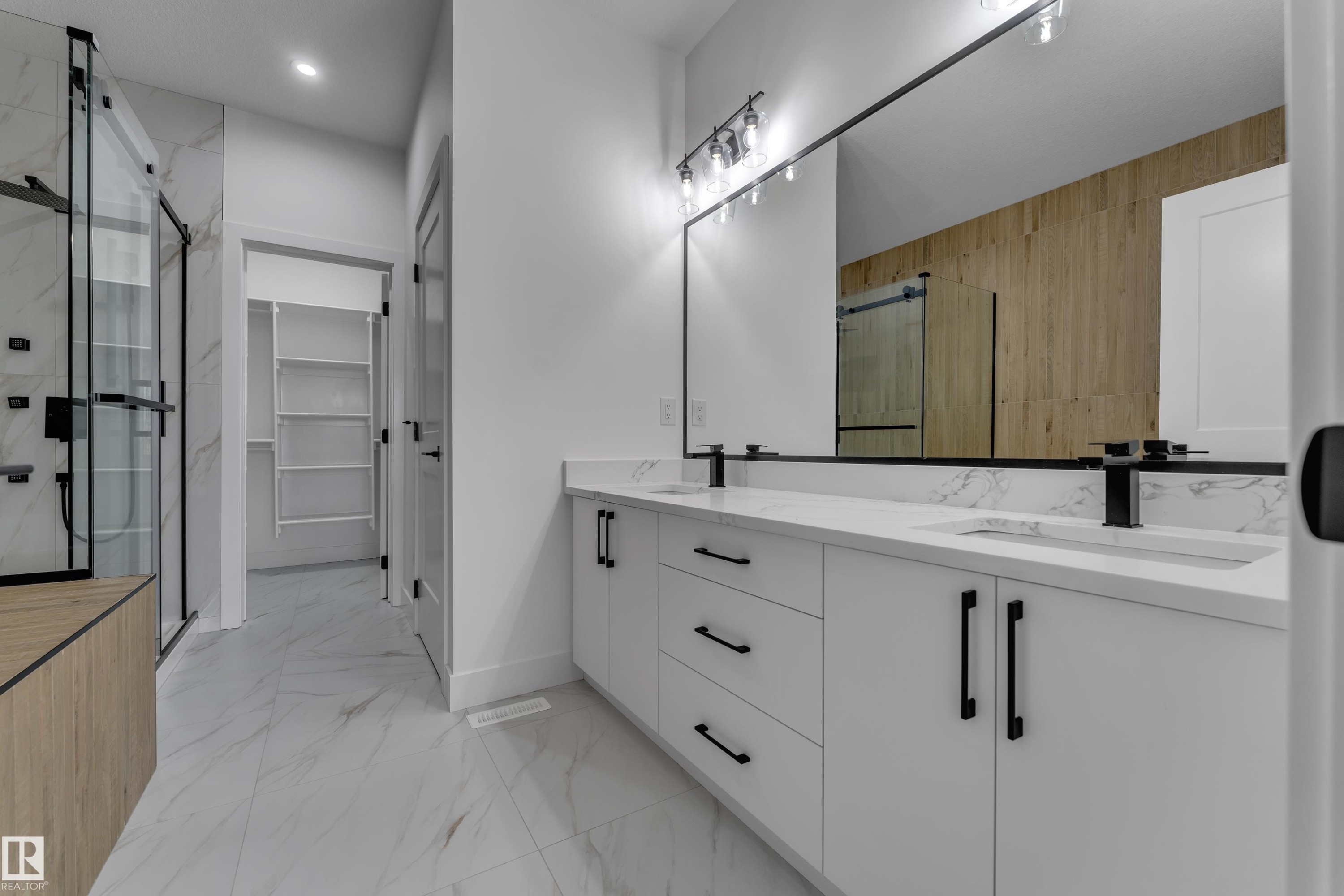 Bathroom featuring a dual vanity with white cabinetry, integrated sinks, and black fixtures - 794 Bank Drive, Leduc, AB