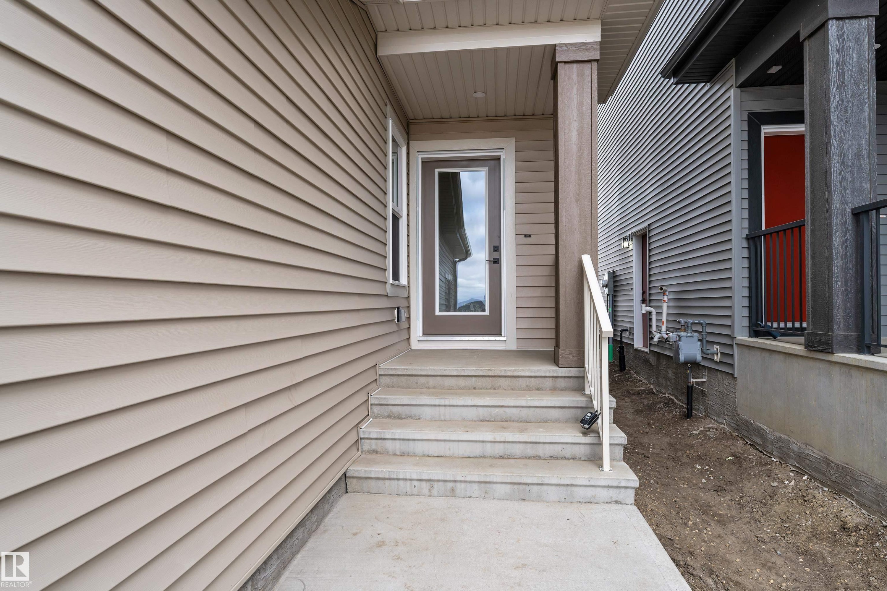 Entry with concrete steps, a full-lite door, and a covered porch - 794 Bank Drive, Leduc, AB