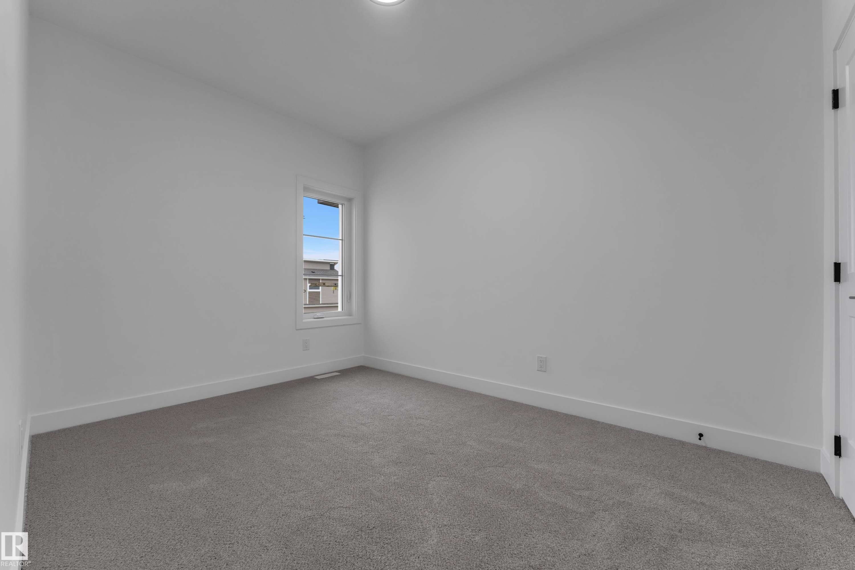 Neutral gray carpeting with white trim, single window, and white interior door with black hardware - 794 Bank Drive, Leduc, AB