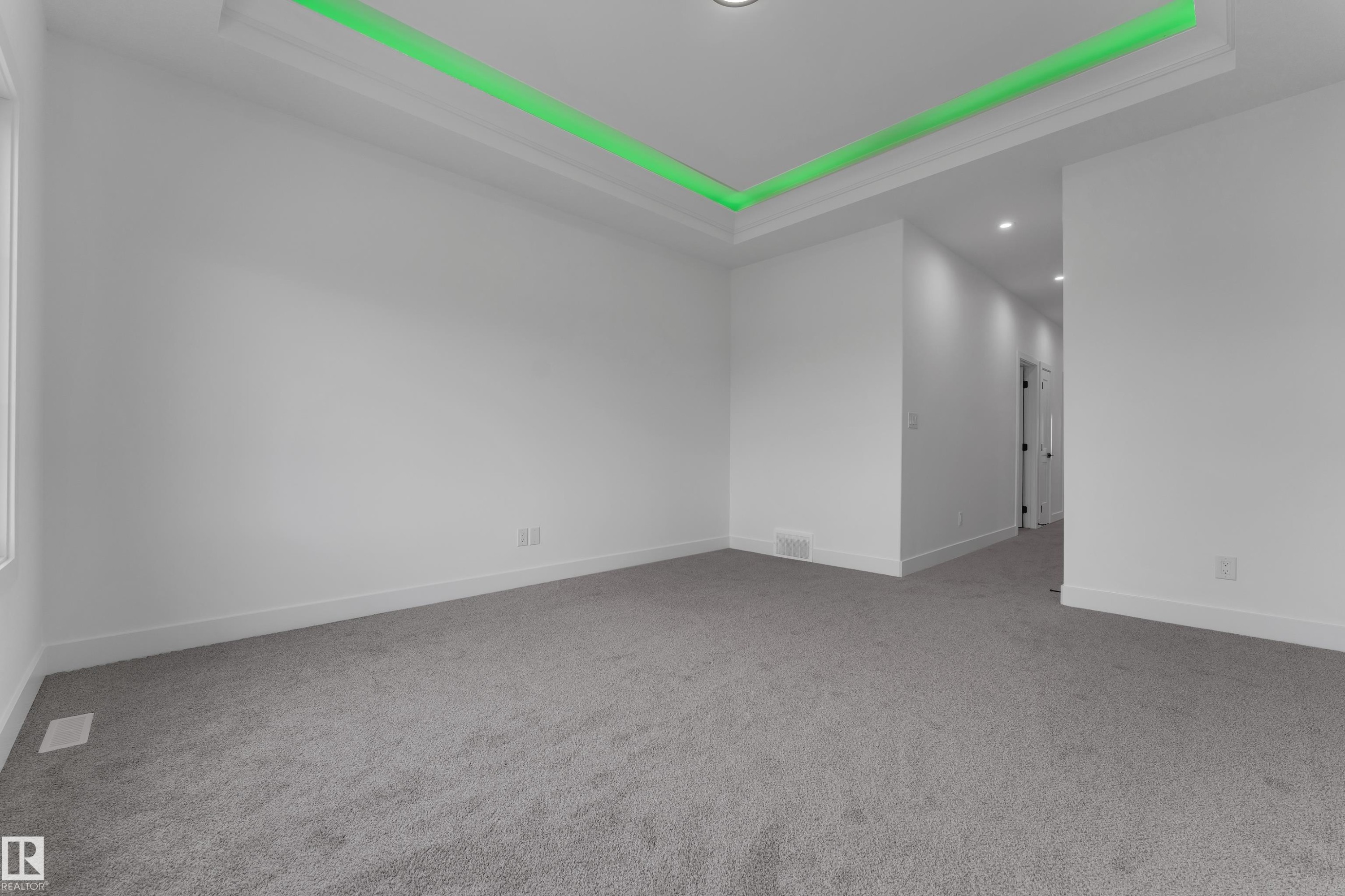 Recessed tray ceiling with accent lighting, neutral carpeting, and white painted walls - 794 Bank Drive, Leduc, AB