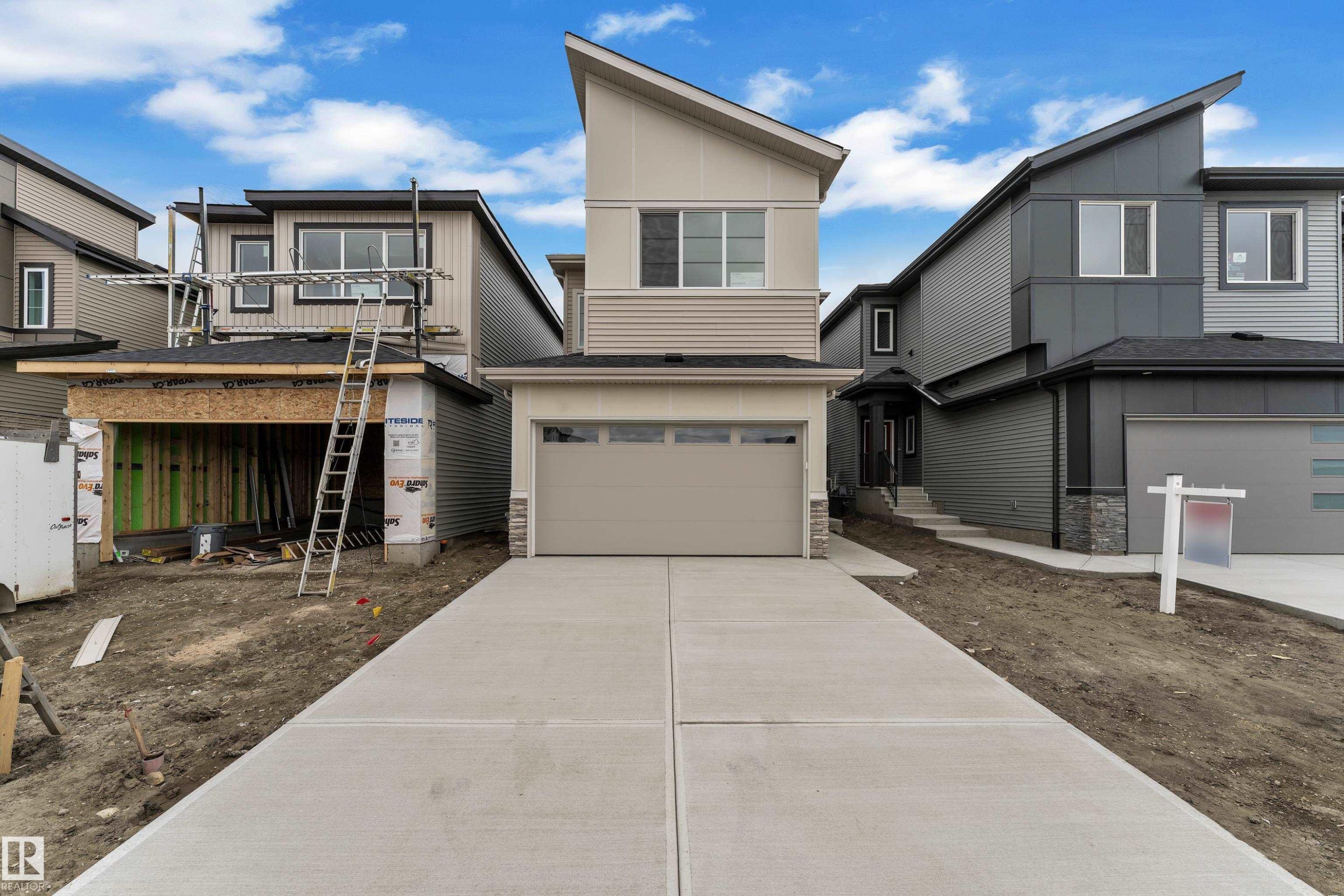 Contemporary exterior with multi-toned siding, stone accents, and an attached garage - 794 Bank Drive, Leduc, AB