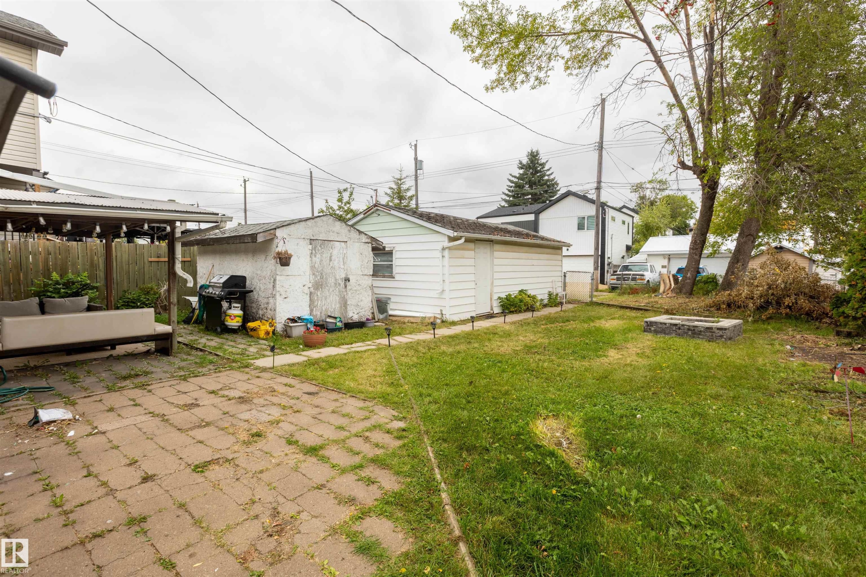 Spacious backyard with mature landscaping and established lawn, complemented by a detached shed structure and paver patio area - 12707 73 Street Nw, Edmonton, AB