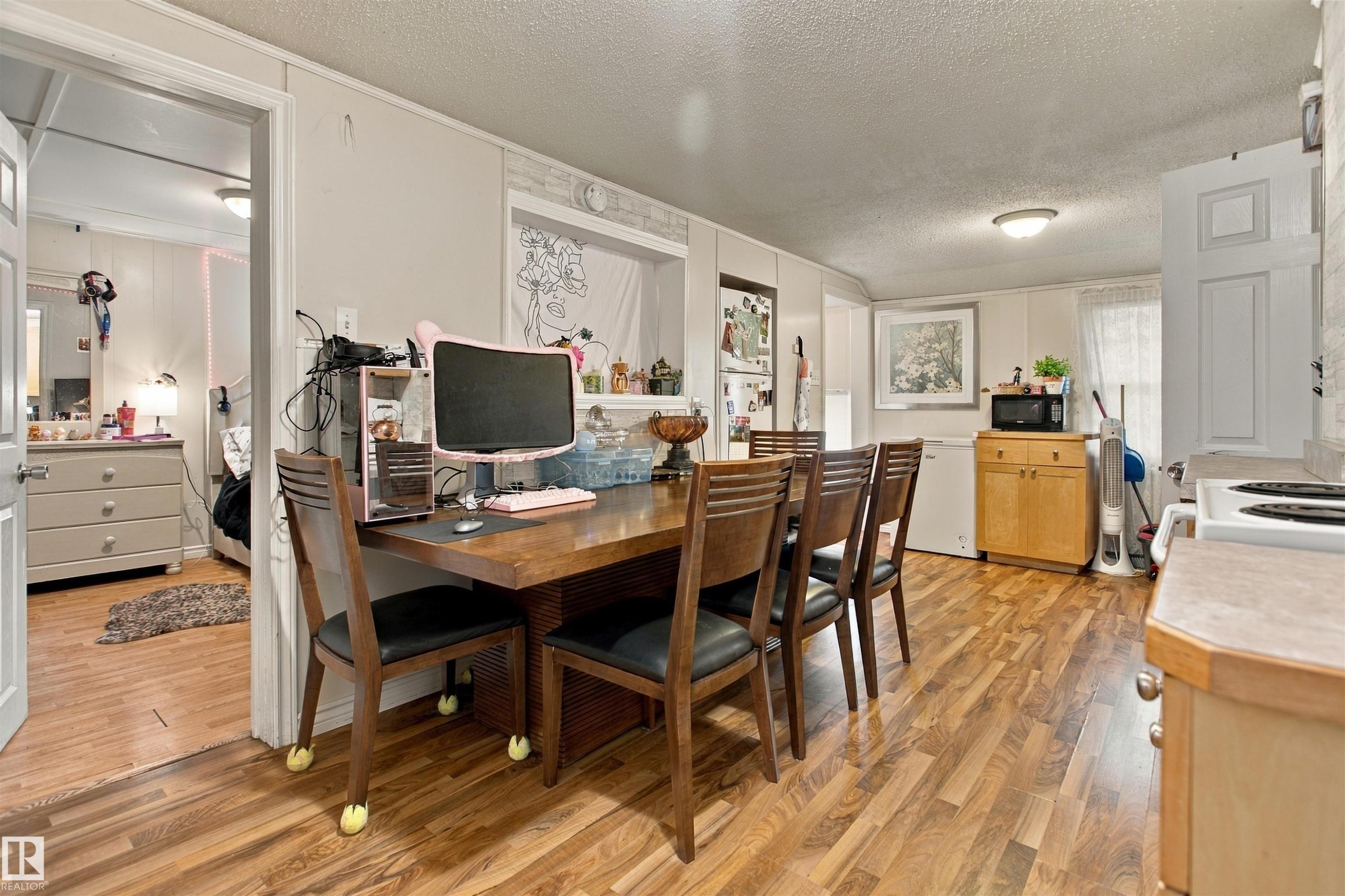 Wood-finish flooring throughout, white wall paneling, and an overhead flush-mount light fixture - 12707 73 Street Nw, Edmonton, AB