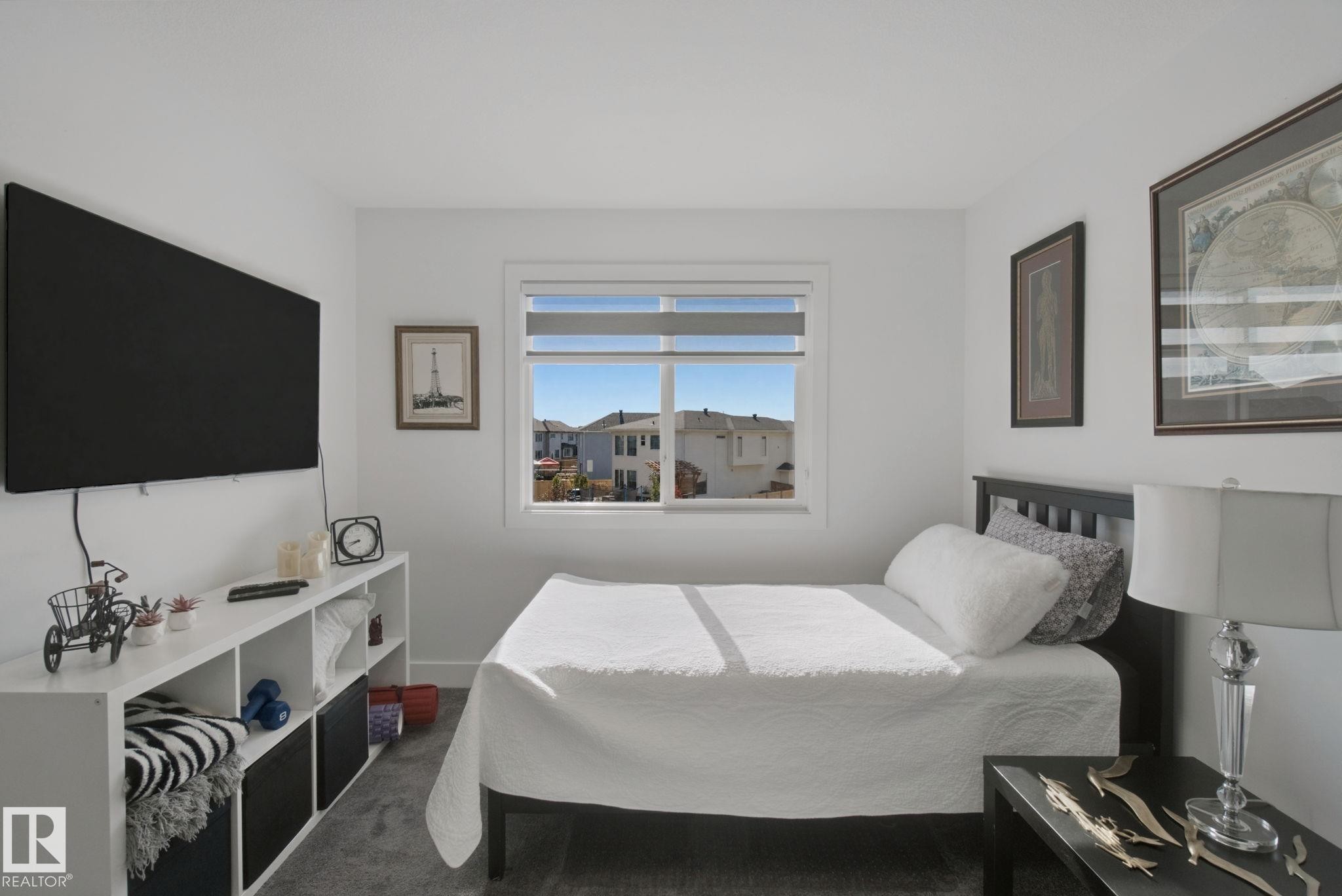 White walls with a window featuring blinds, dark wood-finish flooring, and a built-in shelving unit - 153 Cavanagh Common Sw, Edmonton, AB