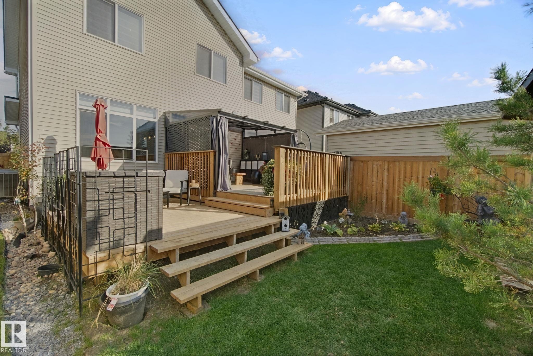 Multi-level wood deck with steps, a privacy screen, and a covered area - 153 Cavanagh Common Sw, Edmonton, AB