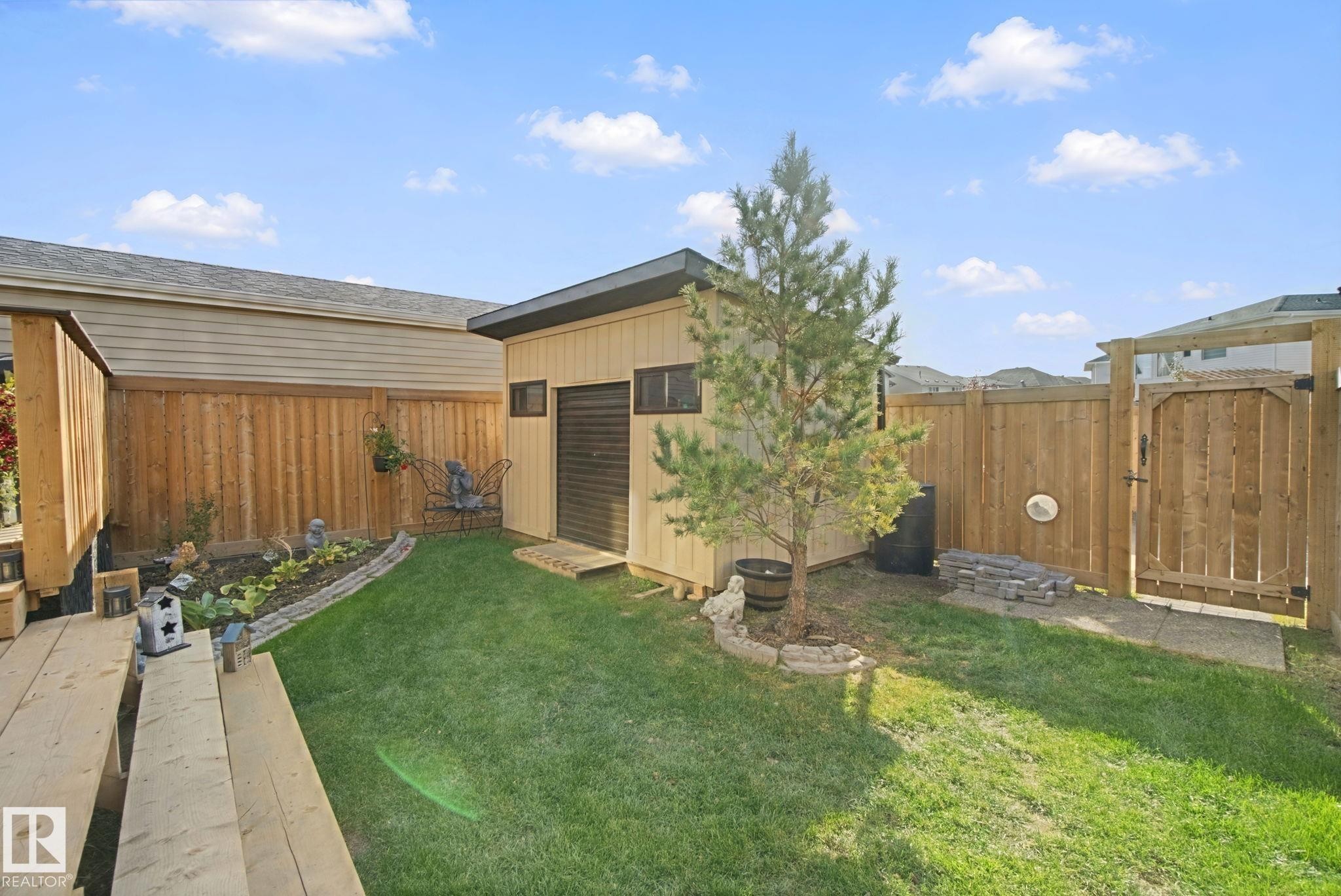 Manicured lawn, wood fencing, garden shed, patio gate, and planted garden bed - 153 Cavanagh Common Sw, Edmonton, AB