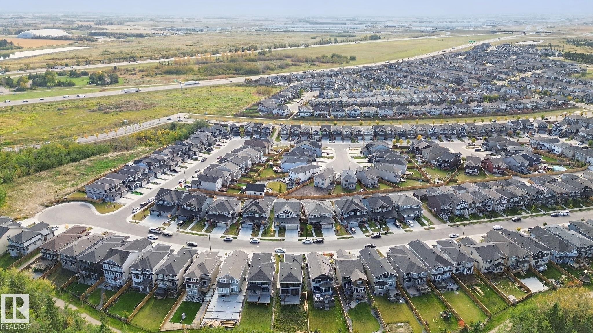 Expansive residential development with numerous single-family homes, each featuring individual driveways - 153 Cavanagh Common Sw, Edmonton, AB