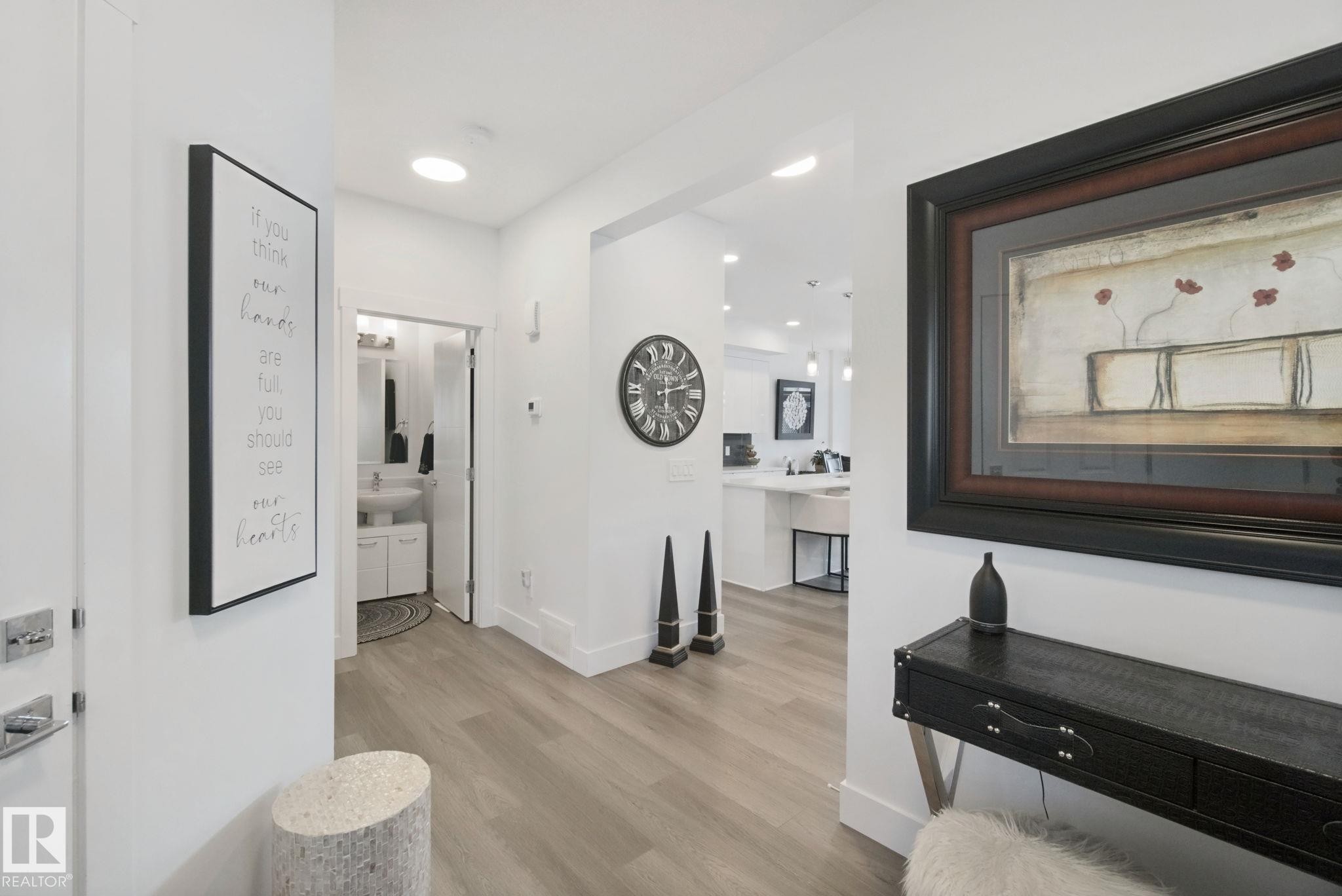 Light wood-finish flooring throughout, recessed lighting, and a white vanity with a rectangular basin sink - 153 Cavanagh Common Sw, Edmonton, AB