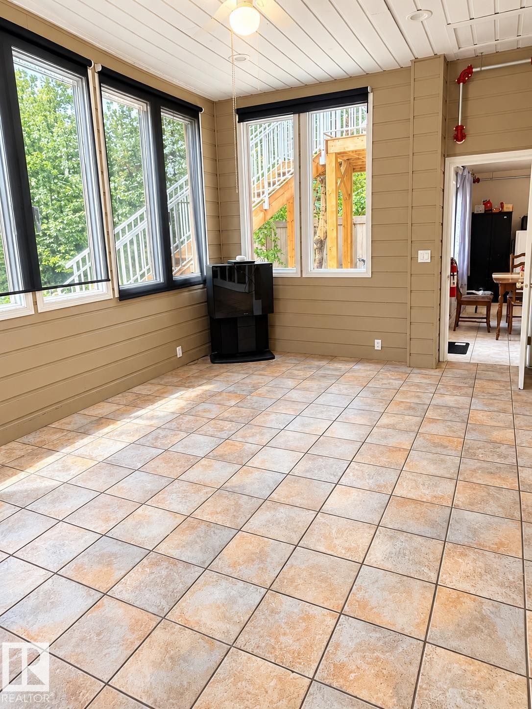 Sunroom featuring tiled flooring, a slatted ceiling, multiple windows, and a ceiling fan - 18929 99A Avenue Nw, Edmonton, AB