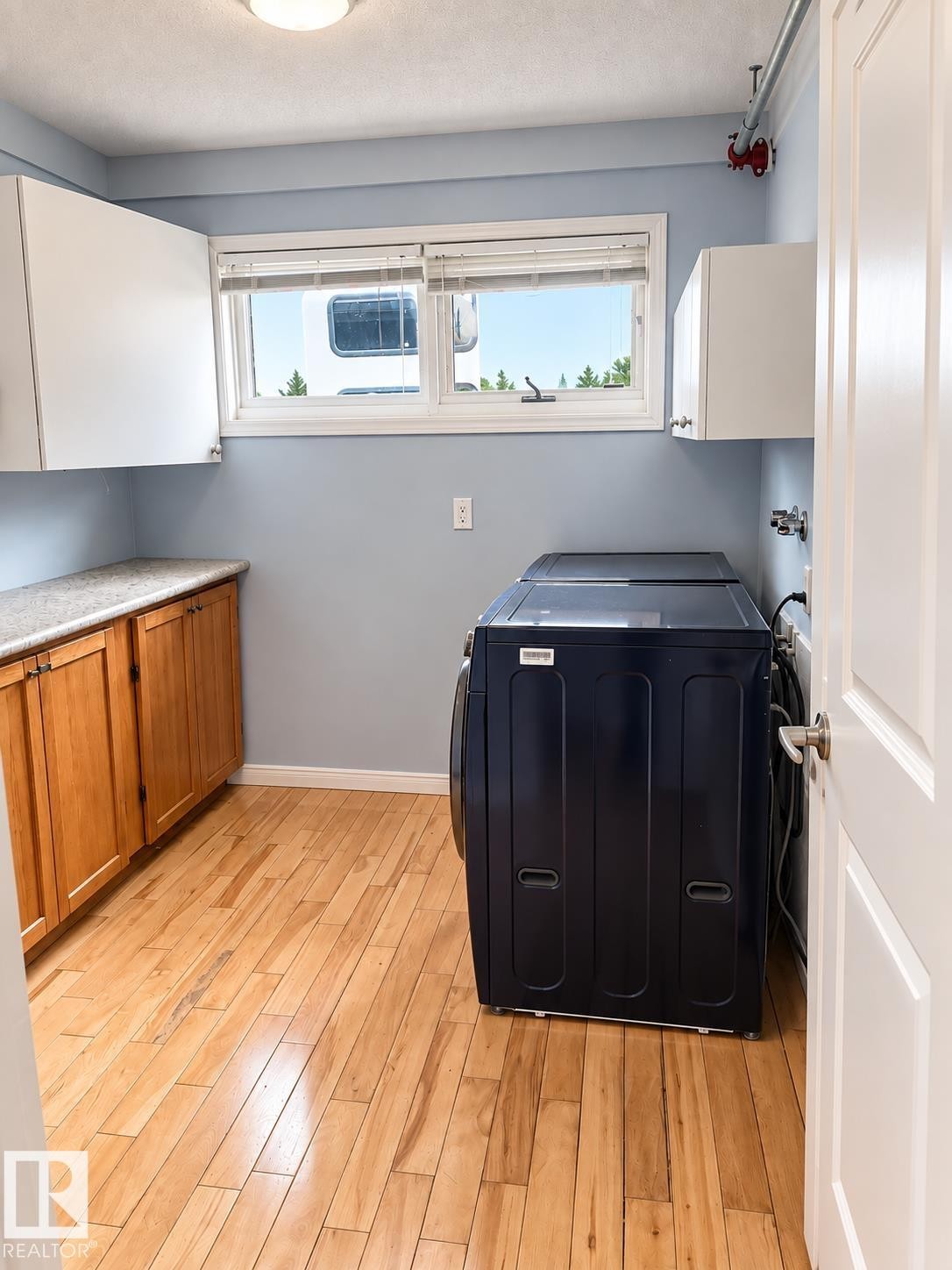 Wood-finish flooring, white overhead cabinetry, and wood-finish lower cabinetry with a light-toned countertop - 18929 99A Avenue Nw, Edmonton, AB