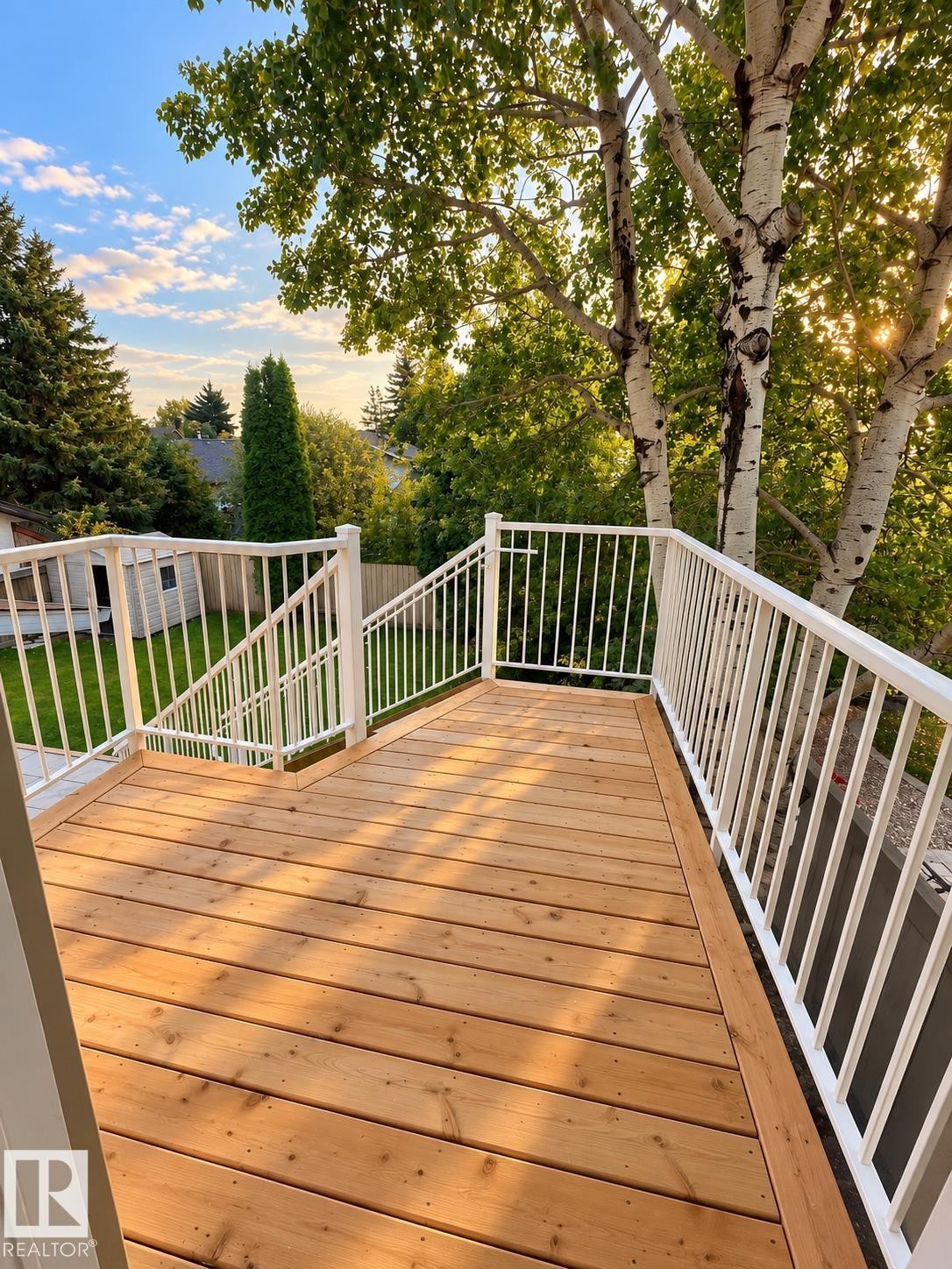 Expansive wood-plank deck with white metal railings, descending to a lower level with additional white metal railings - 18929 99A Avenue Nw, Edmonton, AB