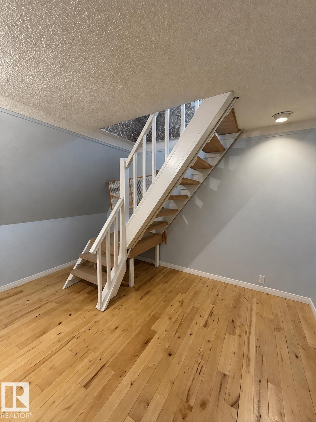 Wood-finish flooring, white wood railings, recessed lighting, light blue wall paint, and white trim - 18929 99A Avenue Nw, Edmonton, AB