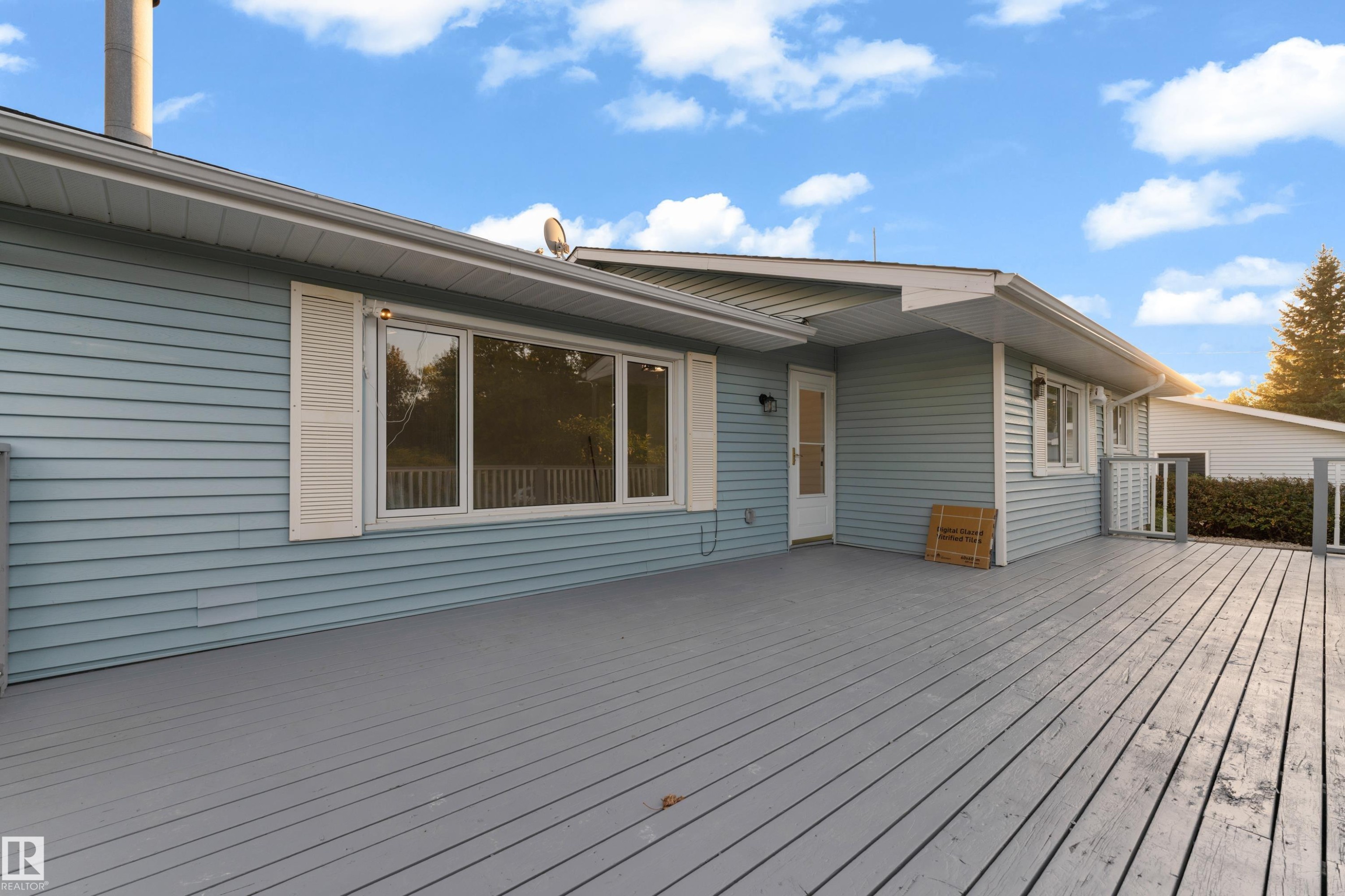 Expansive outdoor deck with gray wood-finish decking, light blue siding, and white window shutters - 52314 Rge Road 215, Rural Strathcona County, AB