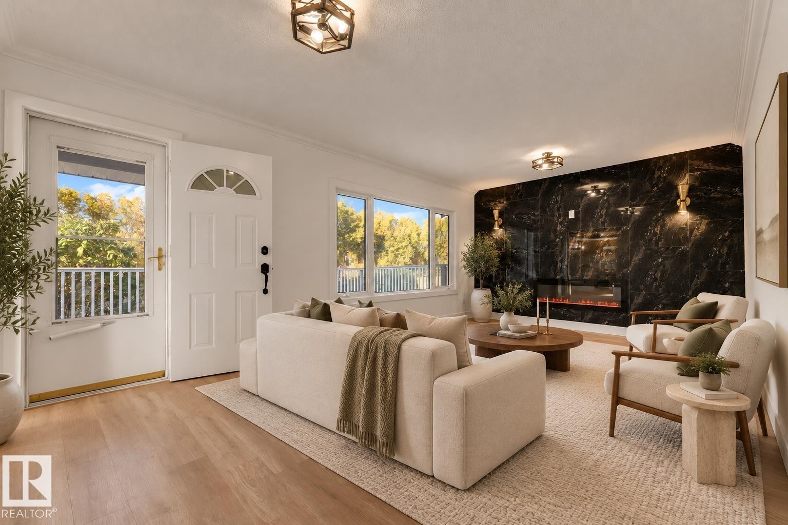 Wood-finish flooring throughout, bright windows, modern fireplace with a dark stone surround, and an entry door with a transom window - 52314 Rge Road 215, Rural Strathcona County, AB
