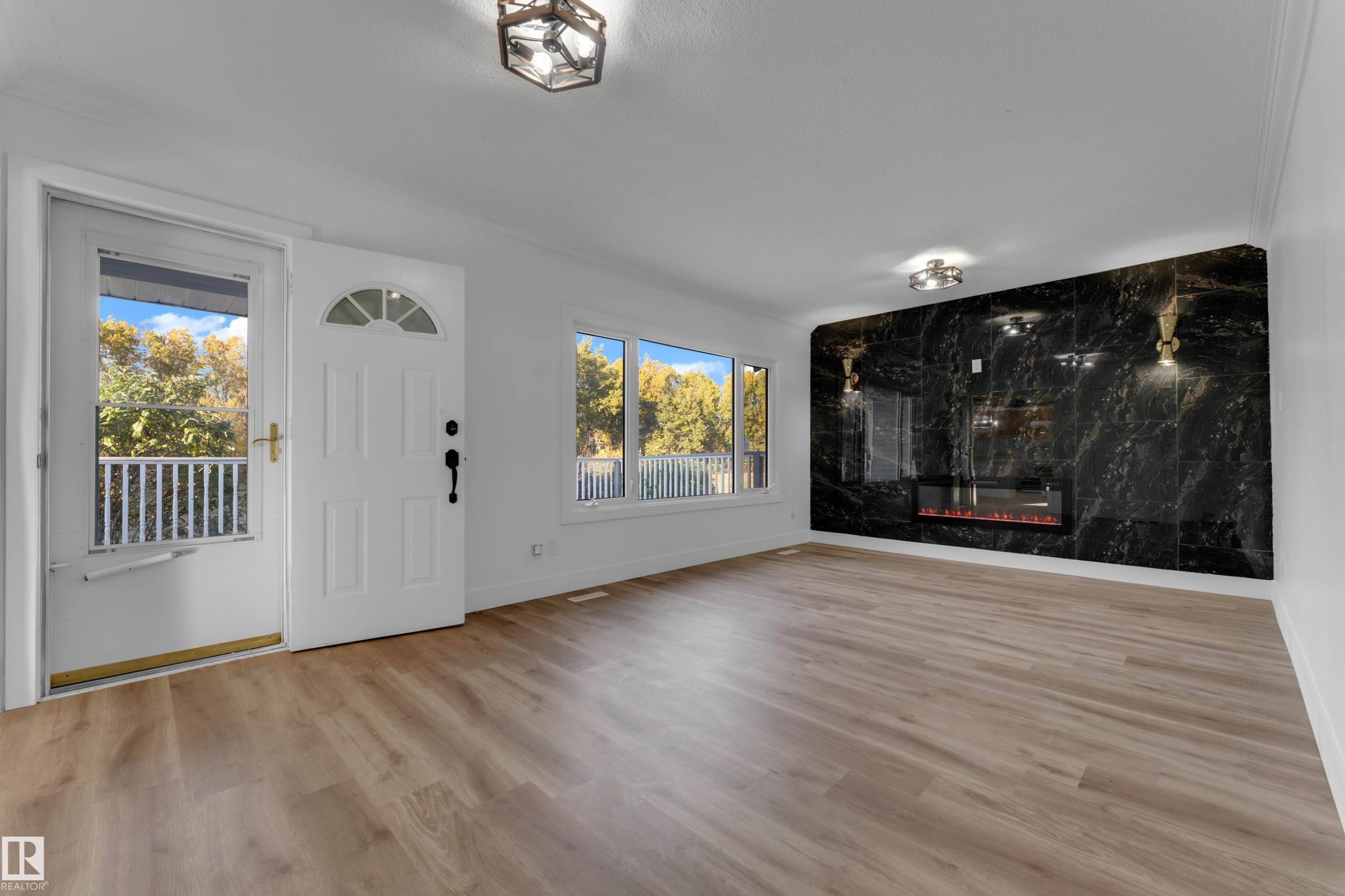 Wood-finish flooring, white walls, and a black stone fireplace wall with an electric insert - 52314 Rge Road 215, Rural Strathcona County, AB