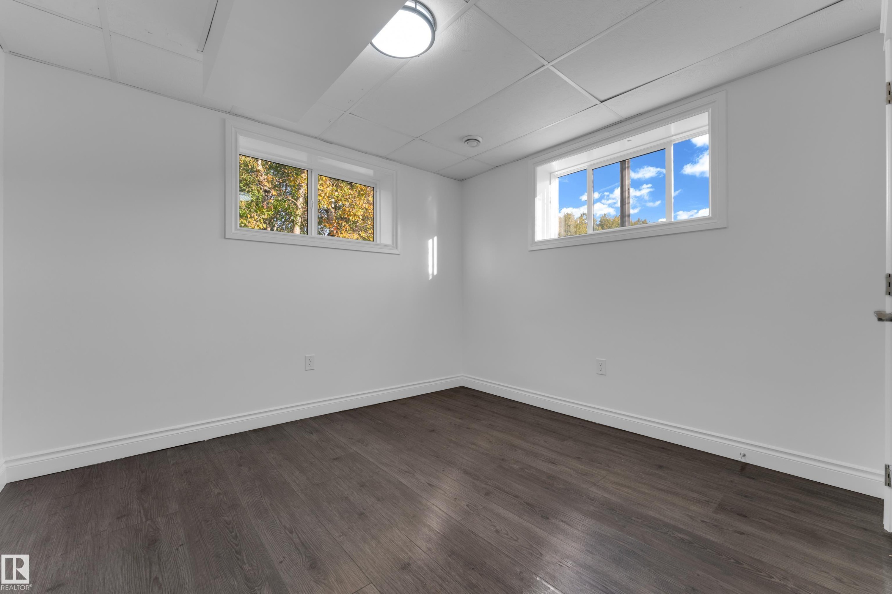 Recessed ceiling light fixture, two windows with white frames, dark wood-finish flooring, and white painted walls - 52314 Rge Road 215, Rural Strathcona County, AB