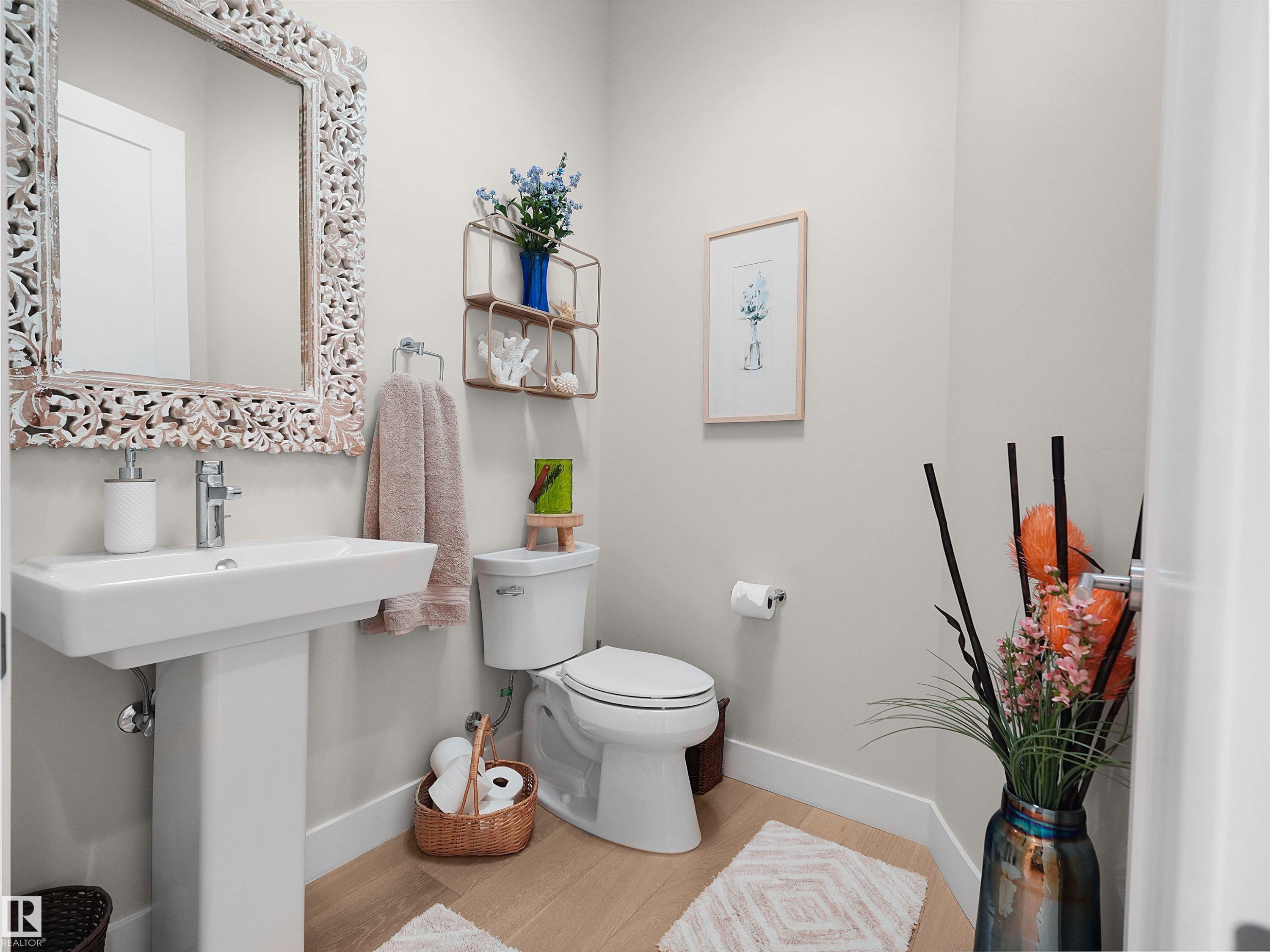 Pedestal sink with a polished chrome faucet, an ornate carved wood-frame mirror, and wood-finish flooring - 904 Wood Place Nw, Edmonton, AB