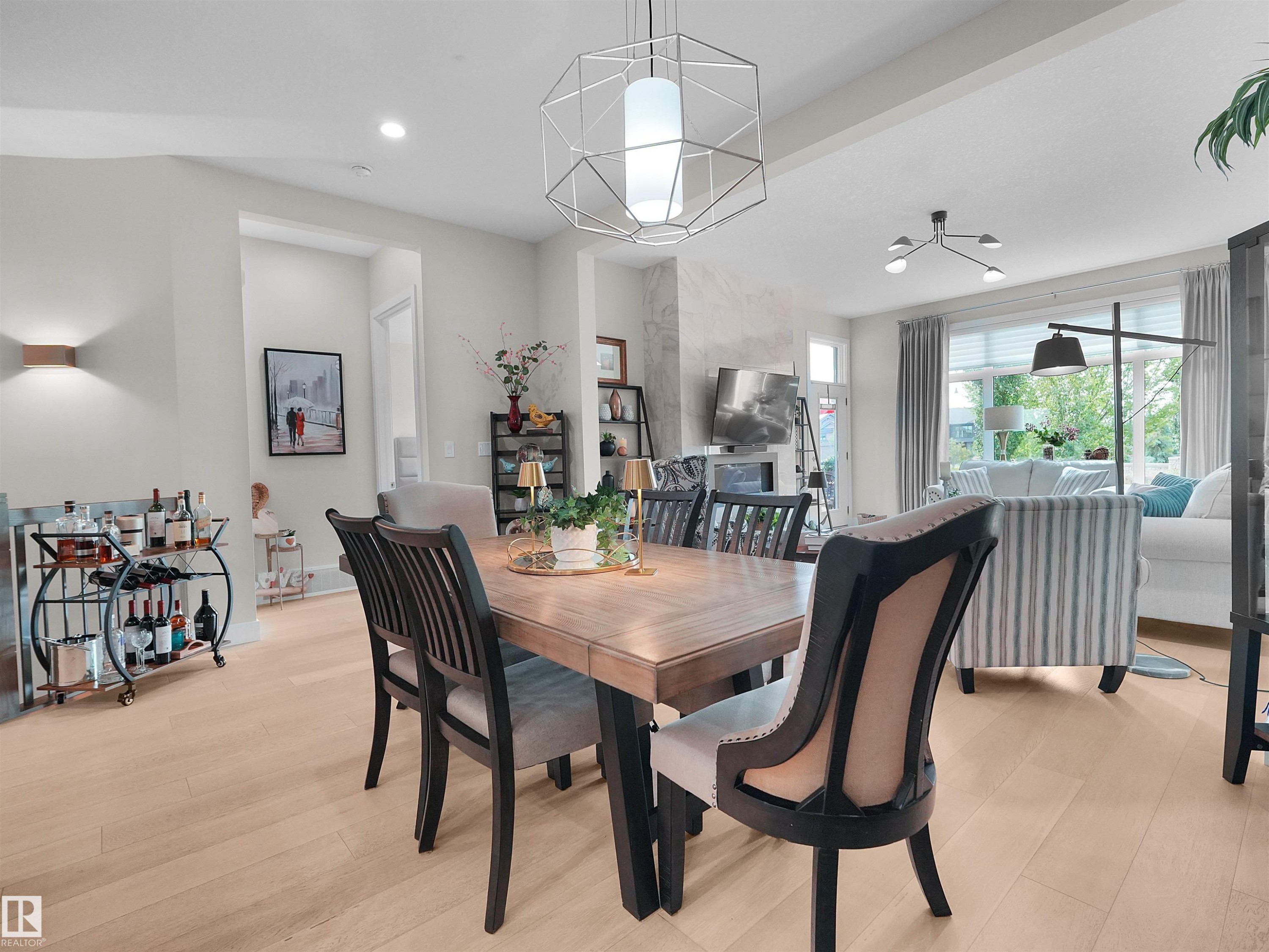 Open-concept living area featuring light wood-finish flooring, recessed lighting, and a modern geometric pendant light fixture - 904 Wood Place Nw, Edmonton, AB