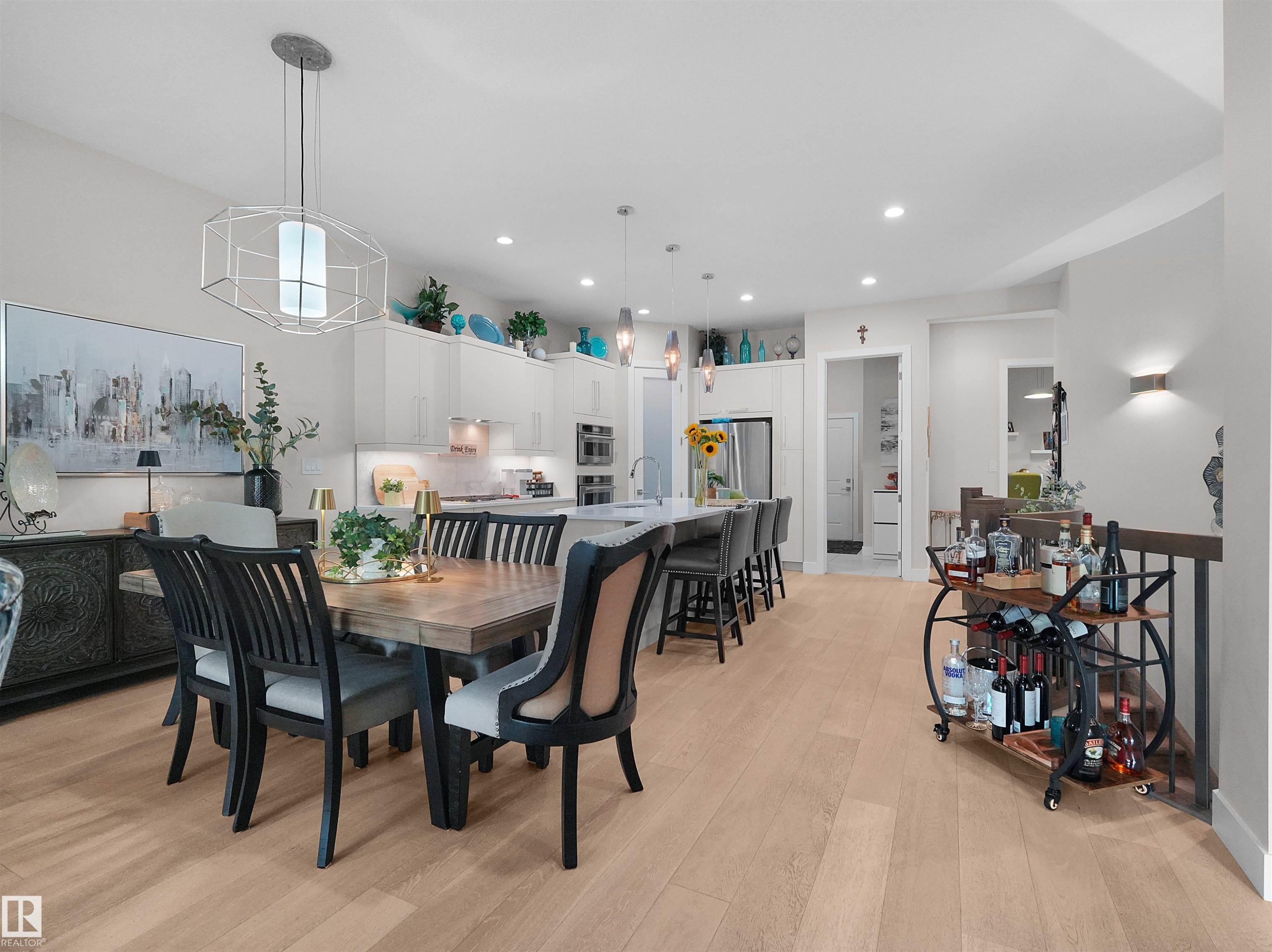 Open-concept living space featuring wood-finish flooring, recessed lighting, and a kitchen with an island, pendant lighting, and stainless steel appliances - 904 Wood Place Nw, Edmonton, AB