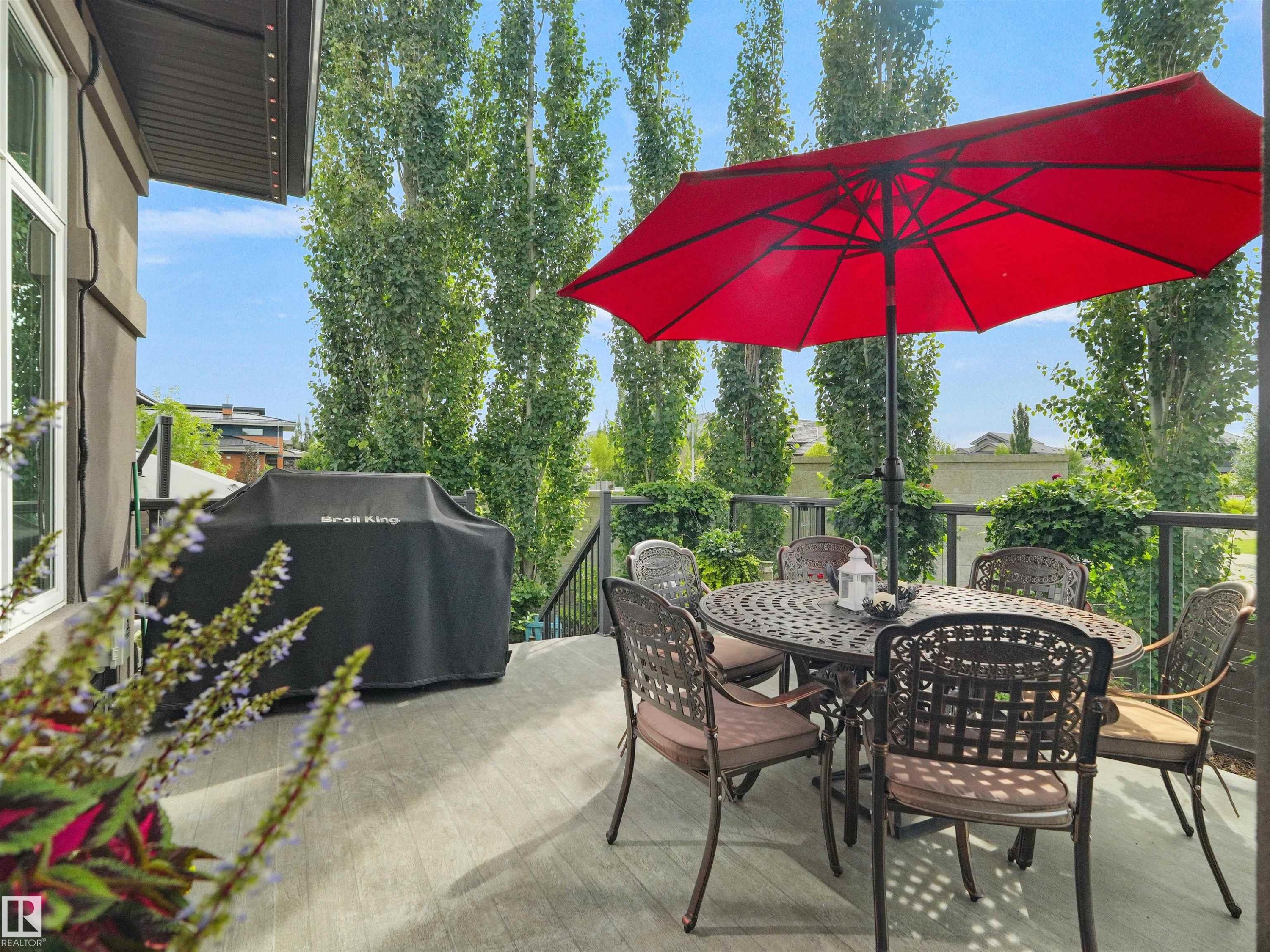 Expansive outdoor deck featuring composite decking, glass panel railings, and mature perimeter trees - 904 Wood Place Nw, Edmonton, AB