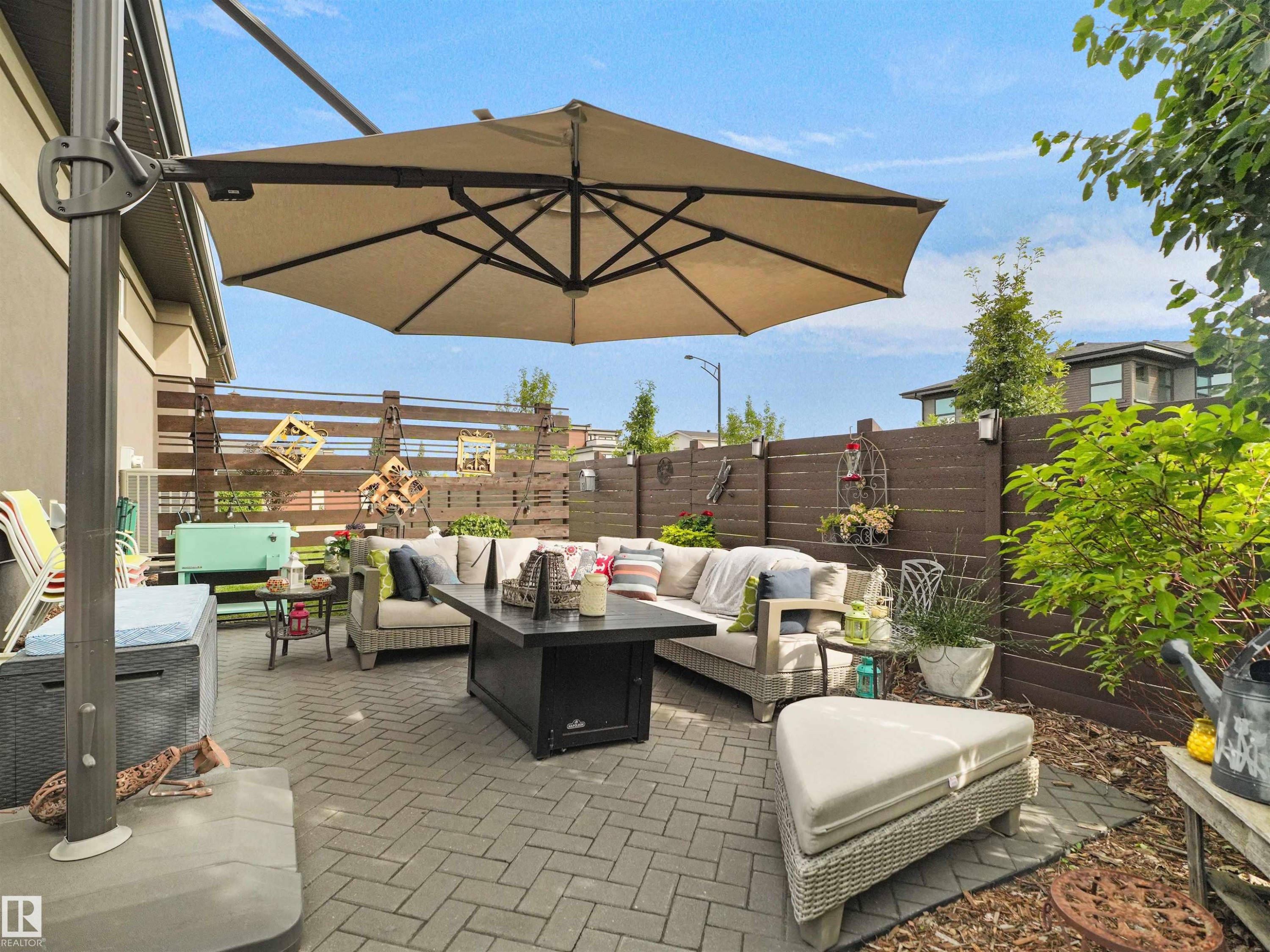 Paved patio area featuring a built-in fire pit, privacy fence, and mature landscaping - 904 Wood Place Nw, Edmonton, AB