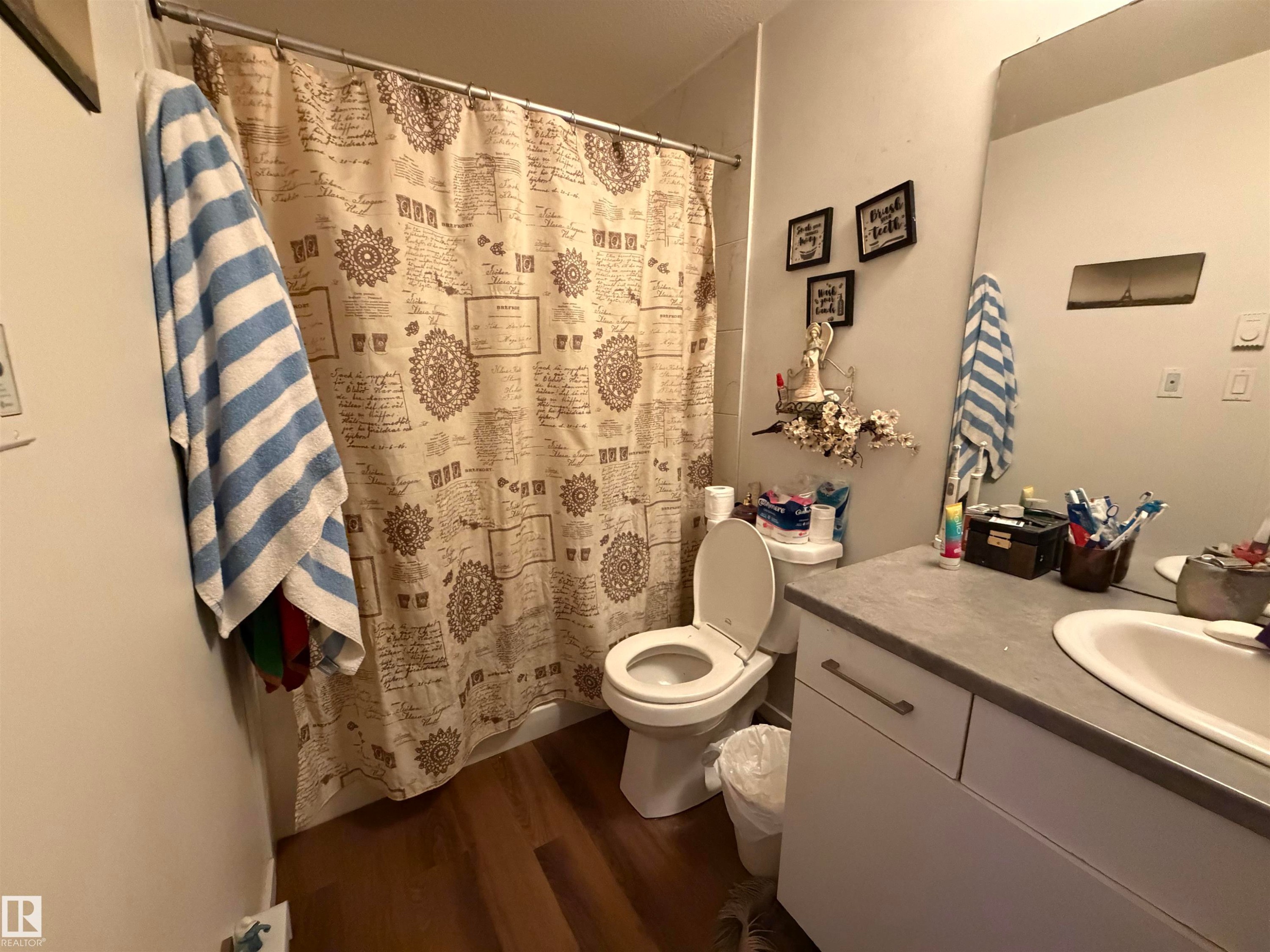 Wood-finish flooring with a vanity featuring a light-toned countertop and integrated sink - 11442 82 Street Nw, Edmonton, AB