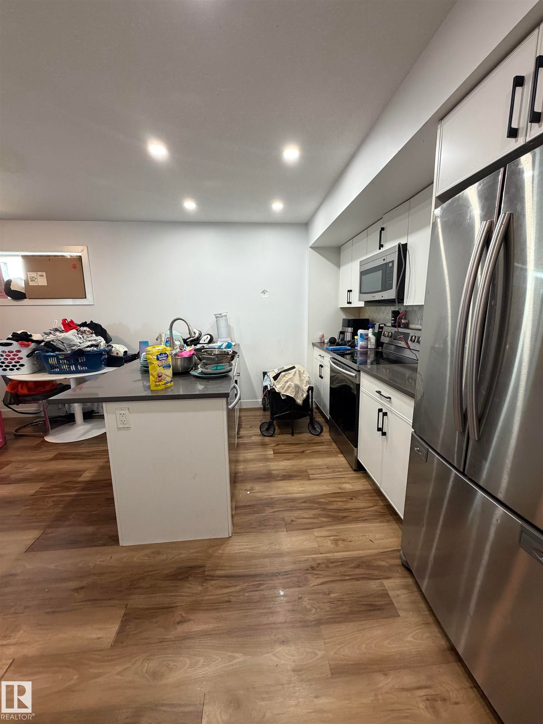 Wood-finish flooring throughout, complemented by recessed ceiling lighting - 11442 82 Street Nw, Edmonton, AB