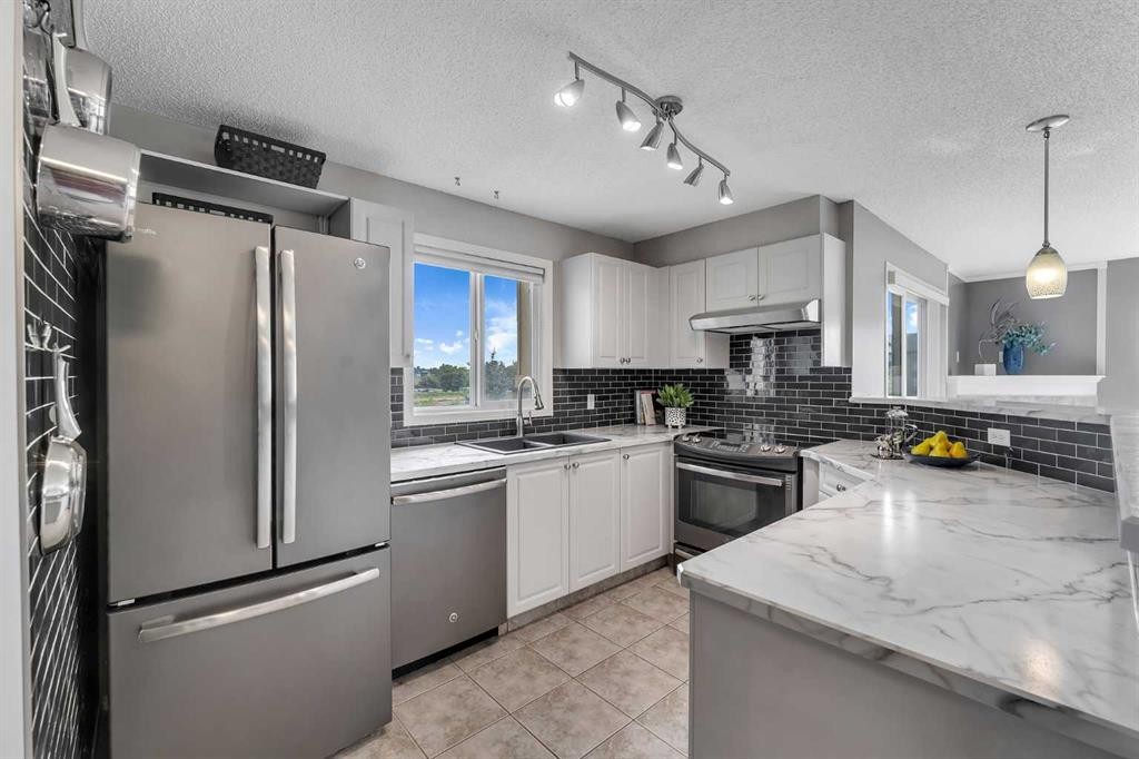 8328-304 Mackenzie Way Sw, Airdrie, AB - Indoor Photo Showing Kitchen With Double Sink