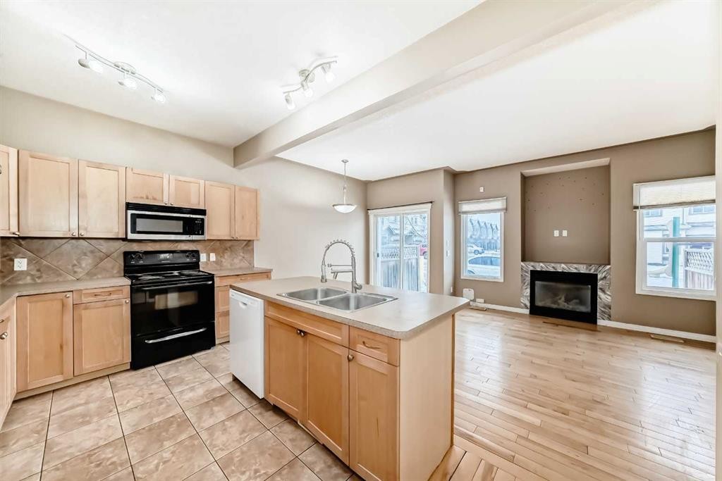207-620 Luxstone Landing Sw, Airdrie, AB - Indoor Photo Showing Kitchen With Fireplace With Double Sink