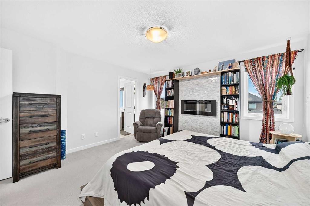 16 Sunrise Crescent, Cochrane, AB - Indoor Photo Showing Bedroom With Fireplace