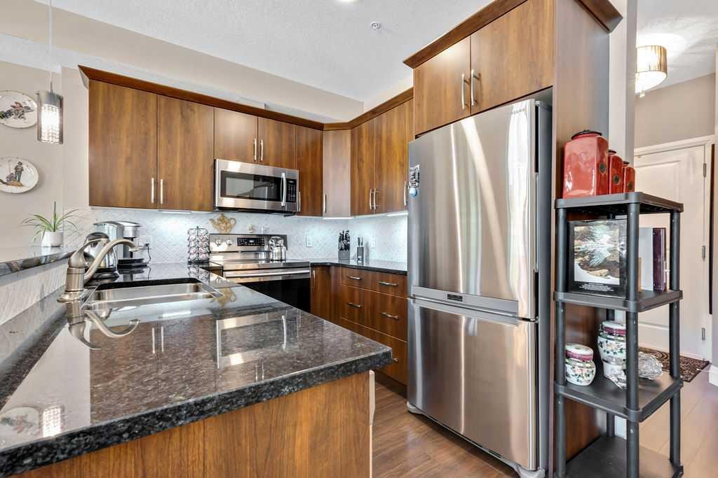 2110-15 Sunset Square, Cochrane, AB - Indoor Photo Showing Kitchen With Stainless Steel Kitchen With Double Sink With Upgraded Kitchen
