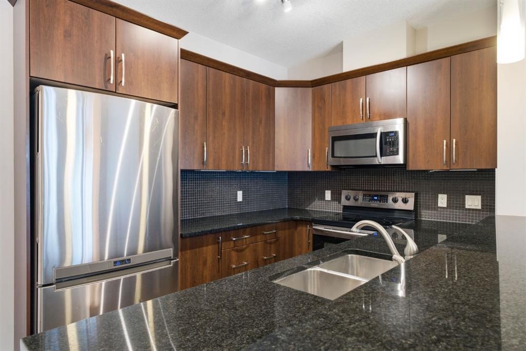 2208-15 Sunset Square, Cochrane, AB - Indoor Photo Showing Kitchen With Stainless Steel Kitchen With Double Sink With Upgraded Kitchen