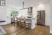 Kitchen with light hardwood / wood-style flooring, stainless steel appliances, hanging light fixtures, wall chimney exhaust hood, and white cabinetry