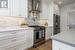 Kitchen with light hardwood / wood-style floors, backsplash, wall chimney exhaust hood, premium appliances, and white cabinets