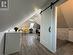 Additional living space with dark wood-type flooring, vaulted ceiling with skylight, and a barn door