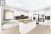 Kitchen featuring decorative backsplash, appliances with stainless steel finishes, white cabinetry, and a kitchen island with sink