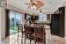 Kitchen featuring sink, a kitchen bar, tasteful backsplash, dark brown cabinetry, and black appliances