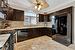 Kitchen featuring sink, decorative backsplash, black appliances, and dark brown cabinetry