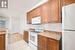 Kitchen with light stone countertops, white appliances, ornamental molding, and light hardwood / wood-style flooring