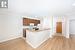 Kitchen with kitchen peninsula, light hardwood / wood-style flooring, white appliances, and ornamental molding