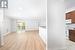 Kitchen featuring light wood-type flooring, white appliances, and ornamental molding