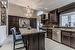 Kitchen featuring a center island, hanging light fixtures, stainless steel appliances, wall chimney range hood, and a notable chandelier