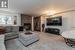 Carpeted living room featuring a stone fireplace and an inviting chandelier