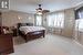 Bedroom featuring multiple windows, ceiling fan, and light carpet