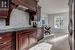 Kitchen with wall chimney range hood, black electric stovetop, dark stone countertops, decorative backsplash, and stainless steel fridge