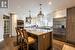 Kitchen with a kitchen island, appliances with stainless steel finishes, white cabinets, hanging light fixtures, and wall chimney exhaust hood