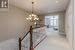 Hall with light colored carpet and a notable chandelier