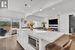 Kitchen with a kitchen breakfast bar, a center island, stainless steel microwave, white cabinetry, and decorative light fixtures